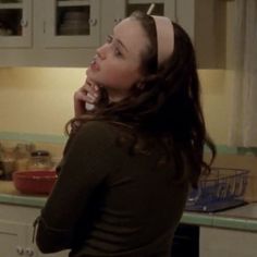 a woman standing in a kitchen talking on a cell phone