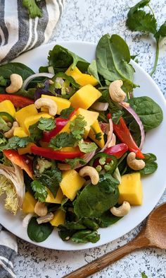 a white plate topped with salad next to a wooden spoon