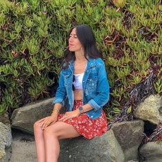 a woman is sitting on some rocks and looking off to the side with her legs crossed