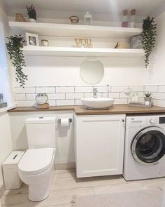 a washer and dryer in a bathroom with plants on the shelves above them