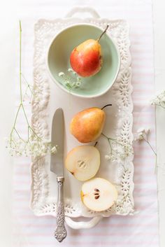 an apple and some sliced apples on a white plate with a knife and fork next to it