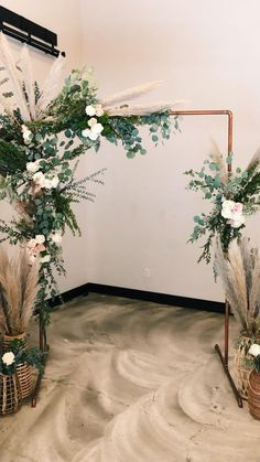 an arch decorated with flowers and greenery in front of a wooden door on the floor