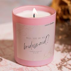 a candle that is sitting on a table with a card in front of it saying, will you be my bridesmaid?