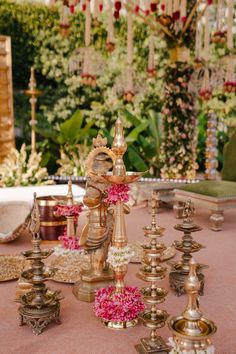 a table topped with lots of gold and pink flowers next to an ornate chandelier