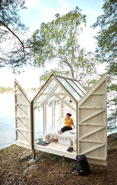 a man sitting on top of a bed in a wooden structure next to a body of water