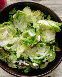 a bowl filled with lettuce on top of a wooden table