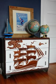 a dresser with a painting on it and a globe sitting on top of it in front of a door