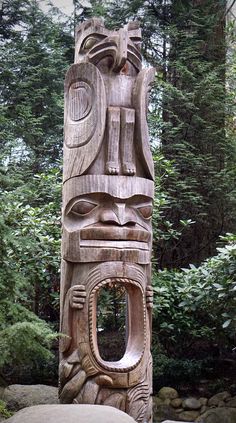 a carved totem stands in front of some trees