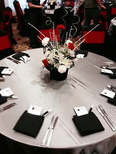 a round table with place settings and silverware on it in a room full of people