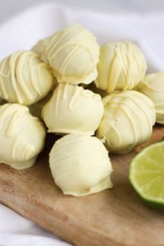 a wooden cutting board topped with lots of white chocolate covered in frosting next to a lime