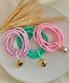 three bracelets with bells are on a plate next to some wheat and a stalk