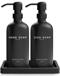 two black soap dispensers sitting on a tray with the words dish soap