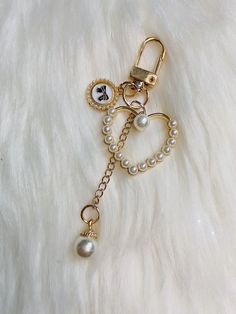 a gold key chain with pearls and charms on top of white furry surface, close up