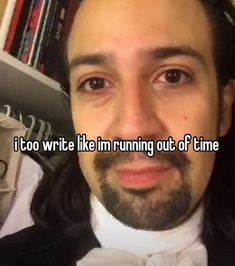 a man with long hair wearing a tuxedo in front of a bookshelf