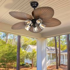 a ceiling fan on the front porch of a house with trees in the back yard