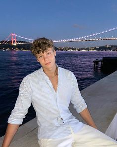 a young man sitting on the edge of a pier