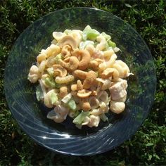 a glass bowl filled with pasta salad on top of green grass