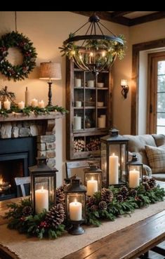 a table topped with candles next to a fire place filled with wreaths and pine cones