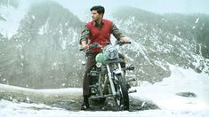 a man sitting on top of a motorcycle in the snow