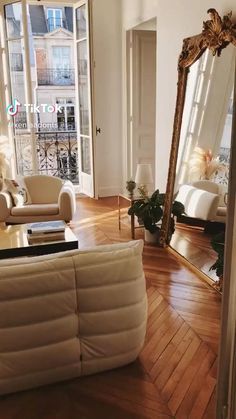 a living room filled with furniture and a large mirror on top of a hard wood floor