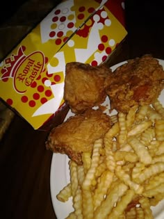 fried chicken and french fries on a plate next to a box of cheetos