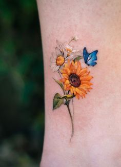 a sunflower and butterfly tattoo on the side of a woman's leg,