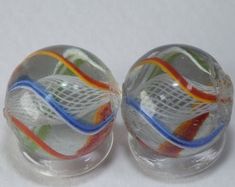 two clear glass beads with multicolored lines on the top and bottom, sitting next to each other