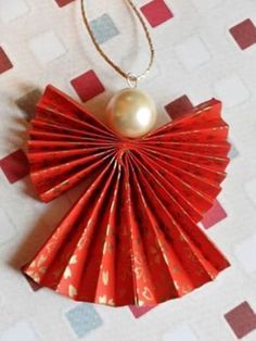 a red origami fan with a pearl hanging from it