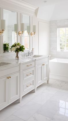 a white bathroom with marble counter tops and large mirrors on the wall above the sinks