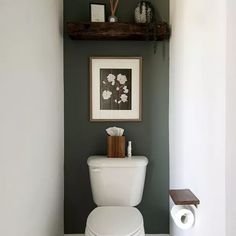 a white toilet sitting in a bathroom next to a shelf with pictures on top of it