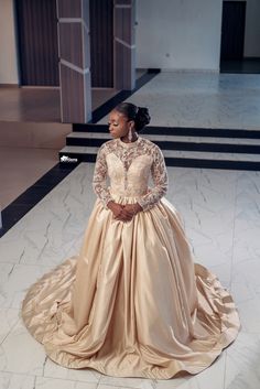 a woman in a long dress standing on the floor with her hands behind her back