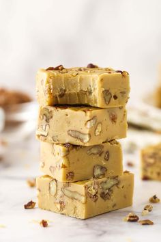 three pieces of fudge are stacked on top of each other with nuts scattered around them