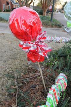 some candy canes wrapped in red and white paper are sitting on the ground next to a christmas tree