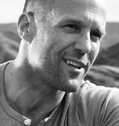 black and white photograph of a man smiling at the camera with mountains in the background