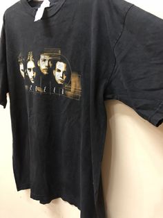 a t - shirt hanging up against a wall with the image of three men on it