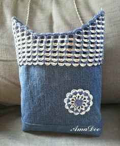 a blue purse sitting on top of a couch next to a chain link bag with an embroidered flower