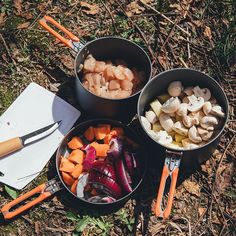 three pans filled with food sitting on the ground next to some utensils