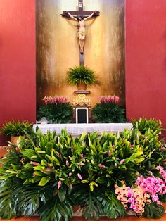 a cross in the middle of a room with plants