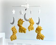 three stuffed giraffes hanging from a mobile in a baby's room