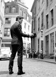 black and white photograph of man in suit holding hands with another man on the street