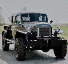 an old truck is parked on the side of the road in front of some grass