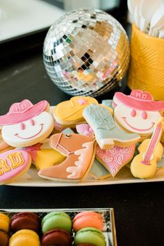 decorated cookies and pastries on a plate with a disco ball in the back ground