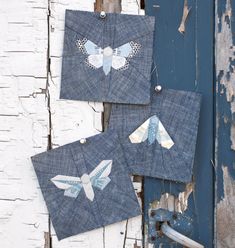 three pieces of fabric with butterflies on them hanging from the side of an old door