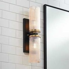 a bathroom light that is on the side of a wall with a mirror behind it