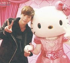 a man standing next to a hello kitty stuffed animal