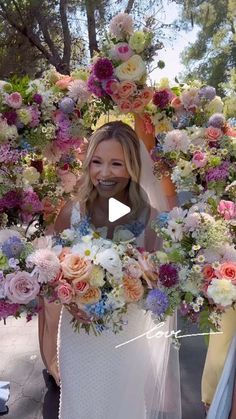 a woman in a white dress is holding flowers and smiling at the camera while another woman stands behind her