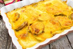 a casserole dish with mushrooms and cheese in it sitting on a wooden table