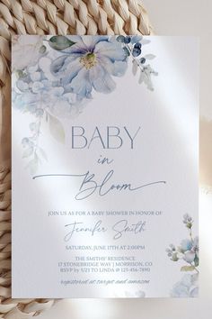 a baby in bloom card with blue flowers on it, sitting next to a wicker basket