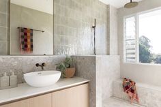 a bathroom with a sink, mirror and bathtub next to a window in it