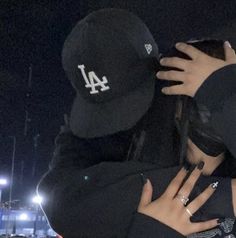 two people hugging each other in front of a baseball field at night with lights on